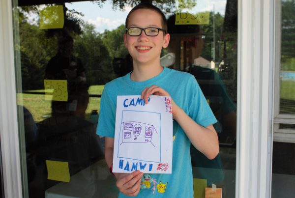 Camper holds a drawing labeled Camp Hamwi