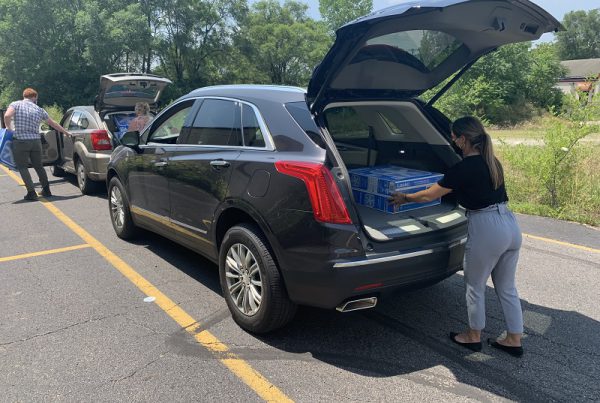 A worker loads fans into a client's car