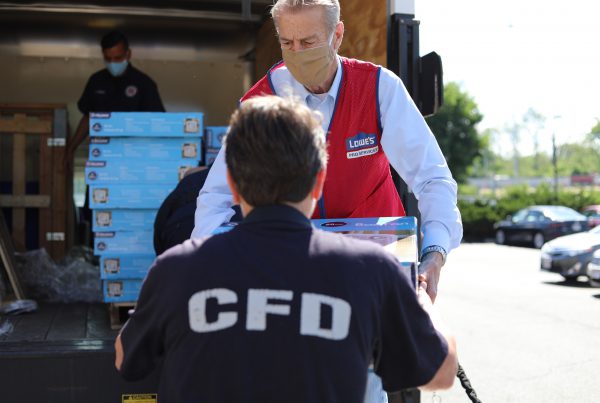 A Lowe's employee hands off a stack of fans to a Columbus firefighter.