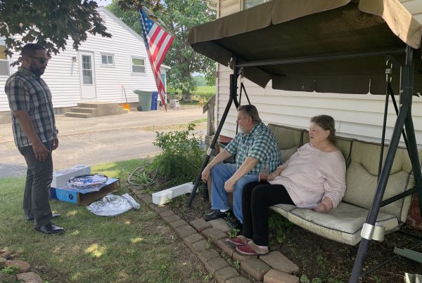 A LifeCare Alliance representative delivers a fan to two clients.
